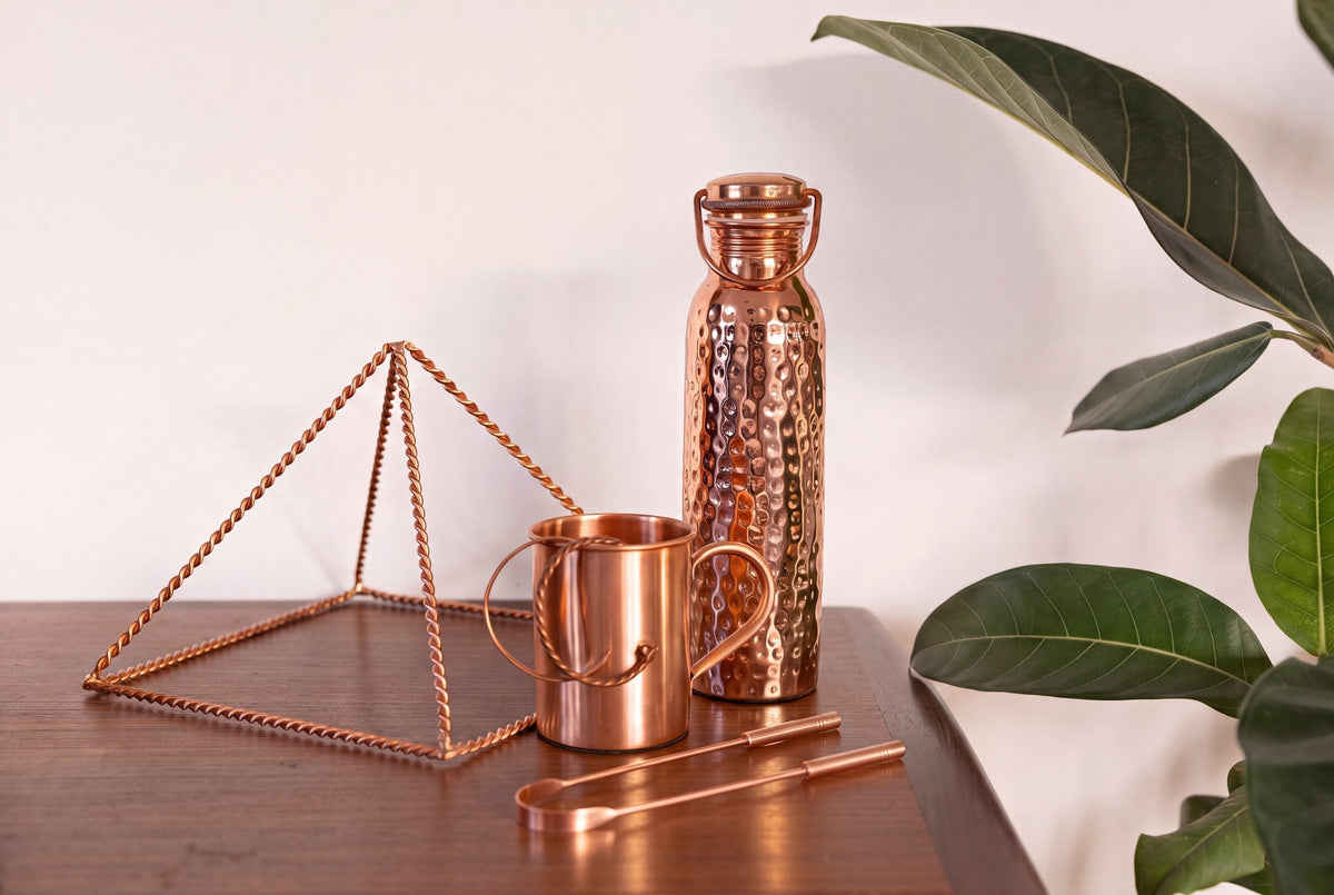 Racle-langue, pyramide, mug et bouteille en cuivre de la collection Kopero réunis sur une table en bois