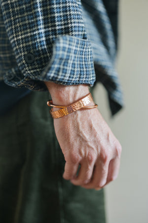 Kopero Bracelet en cuivre Martelé, au poignet sur une manche de chemise à carreaux, avec un bracelet lisse