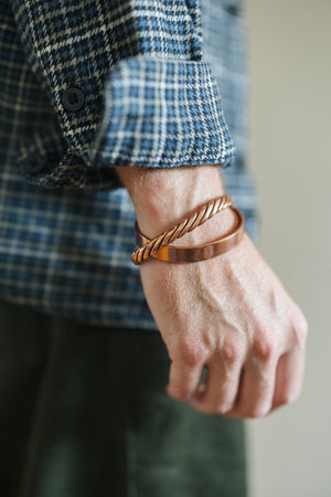 Kopero Bracelet en cuivre Lisse, au poignet sur une manche de chemise à carreaux, avec un bracelet torsadé