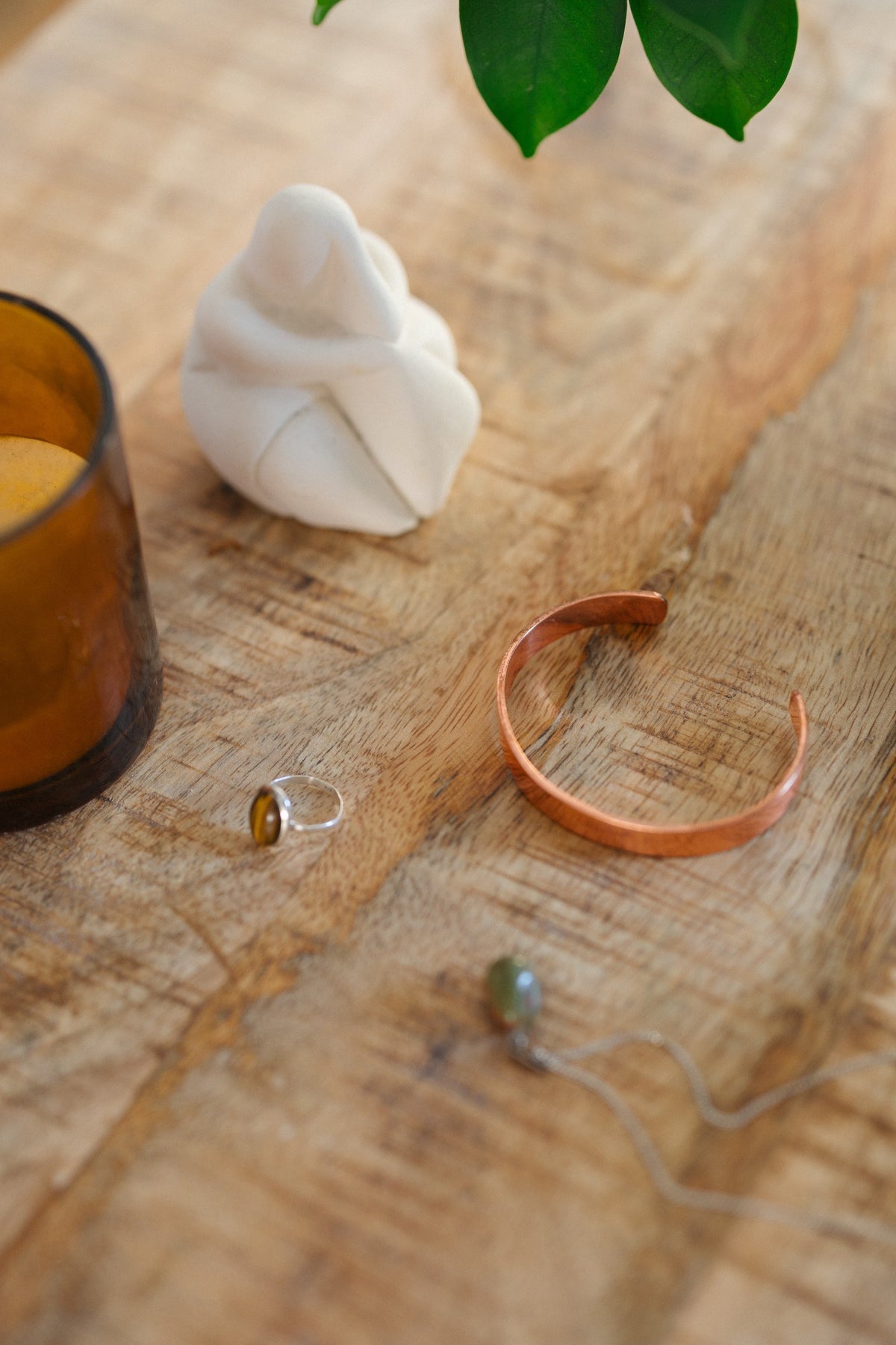 Kopero Bracelet en cuivre Lisse, sur une table en bois à côté d'une figurine et d'une bague