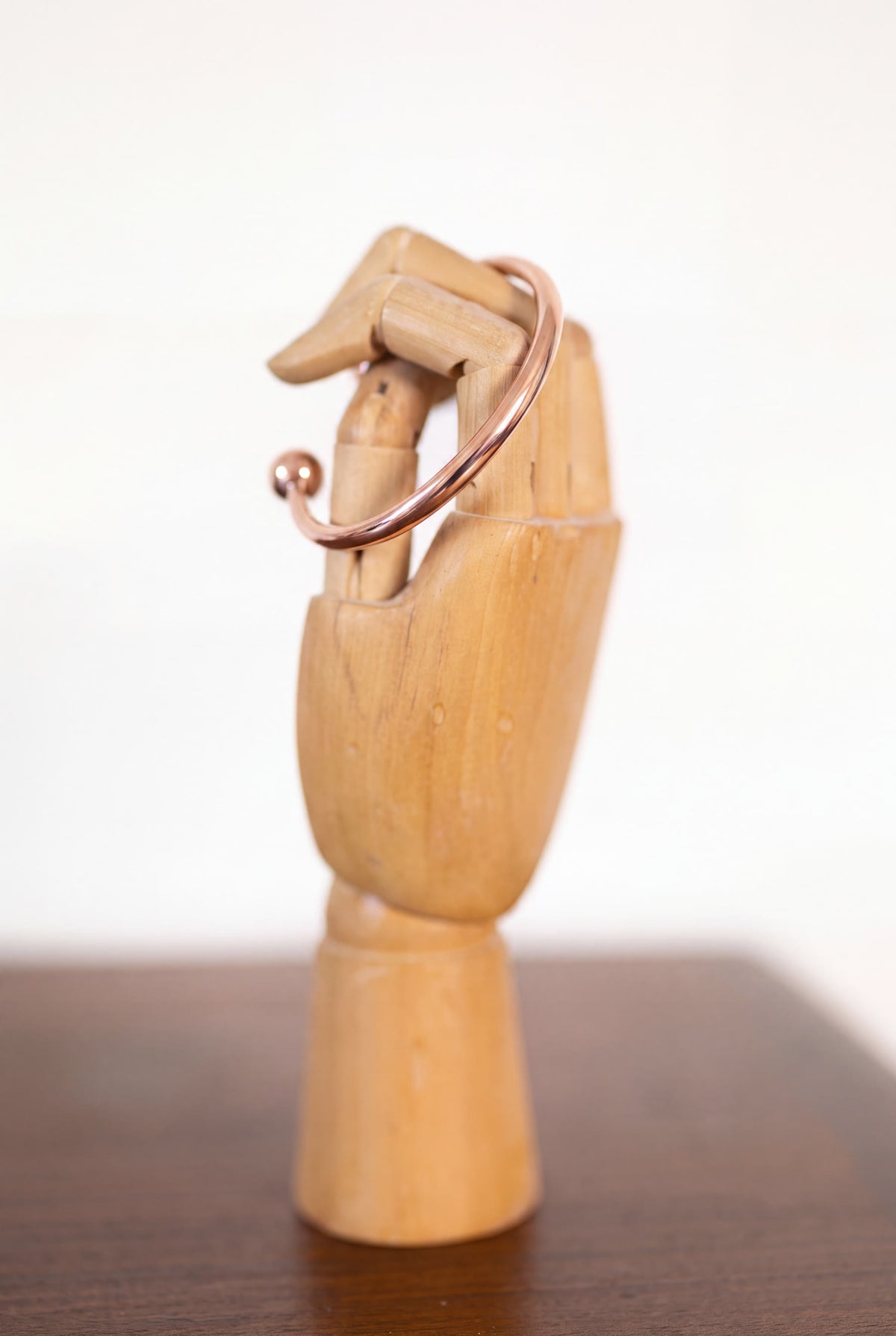 Bracelet en cuivre rond Kopero sur une main à bijoux en bois