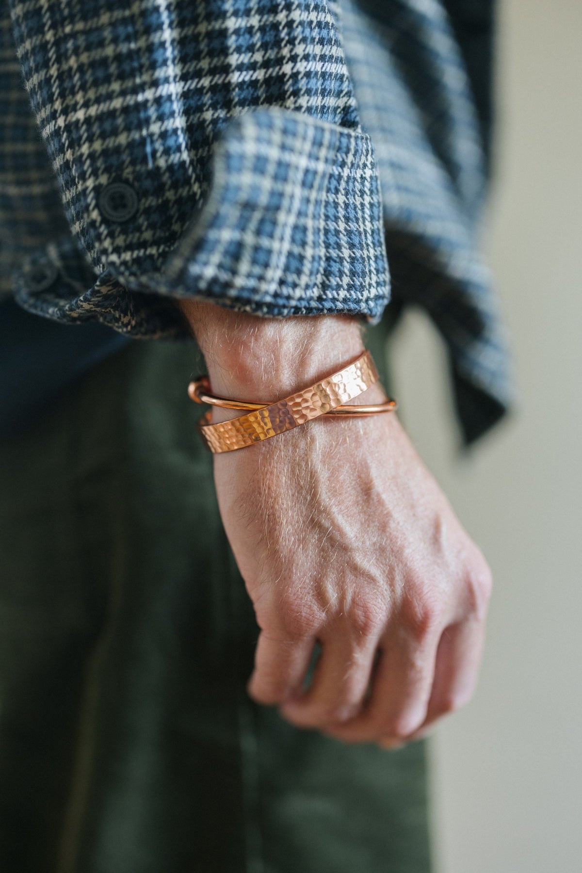 Kopero Bracelet en cuivre Rond, au poignet sur une manche de chemise à carreaux, avec un bracelet martelé