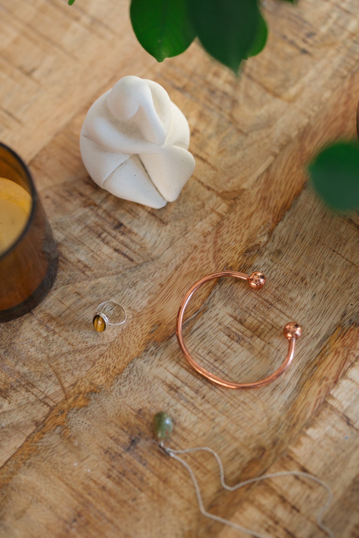 Kopero Bracelet en cuivre Rond, sur une table en bois à côté d'une figurine et d'une bague