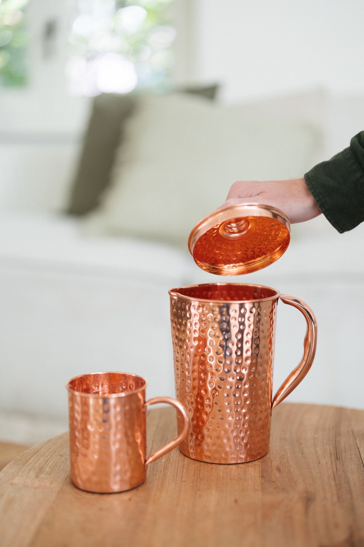 Kopero Cruche en cuivre Martelé, pendant que le couvercle est soulevé, avec un mug à côté