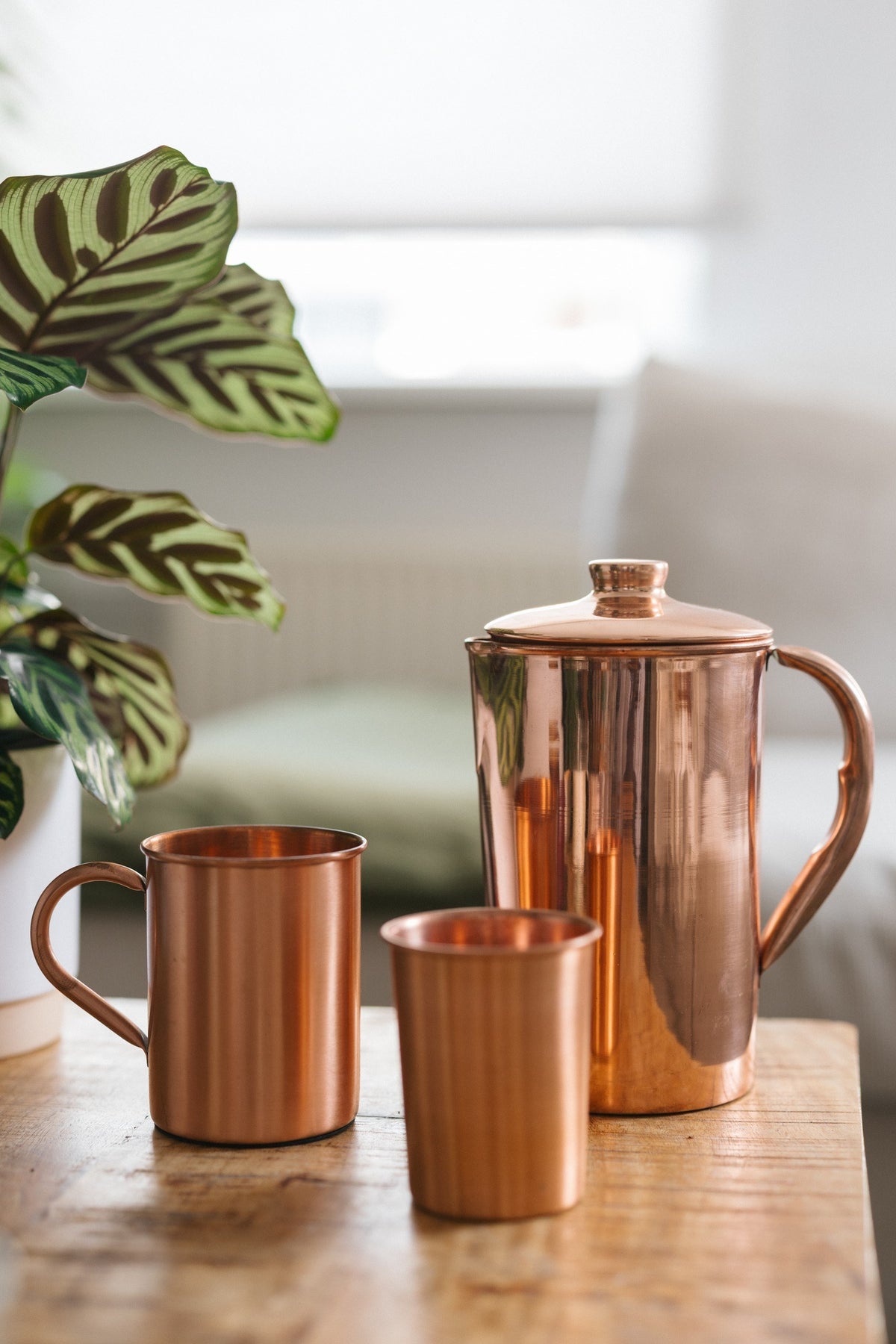 Kopero Cruche en cuivre Lisse, avec un mug et un gobelet sur une table en bois