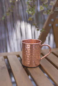 Mug en cuivre Kopero Premium Martelé, 400 ml, 100% cuivre pur, en extérieur sur une table de jardin en bois
