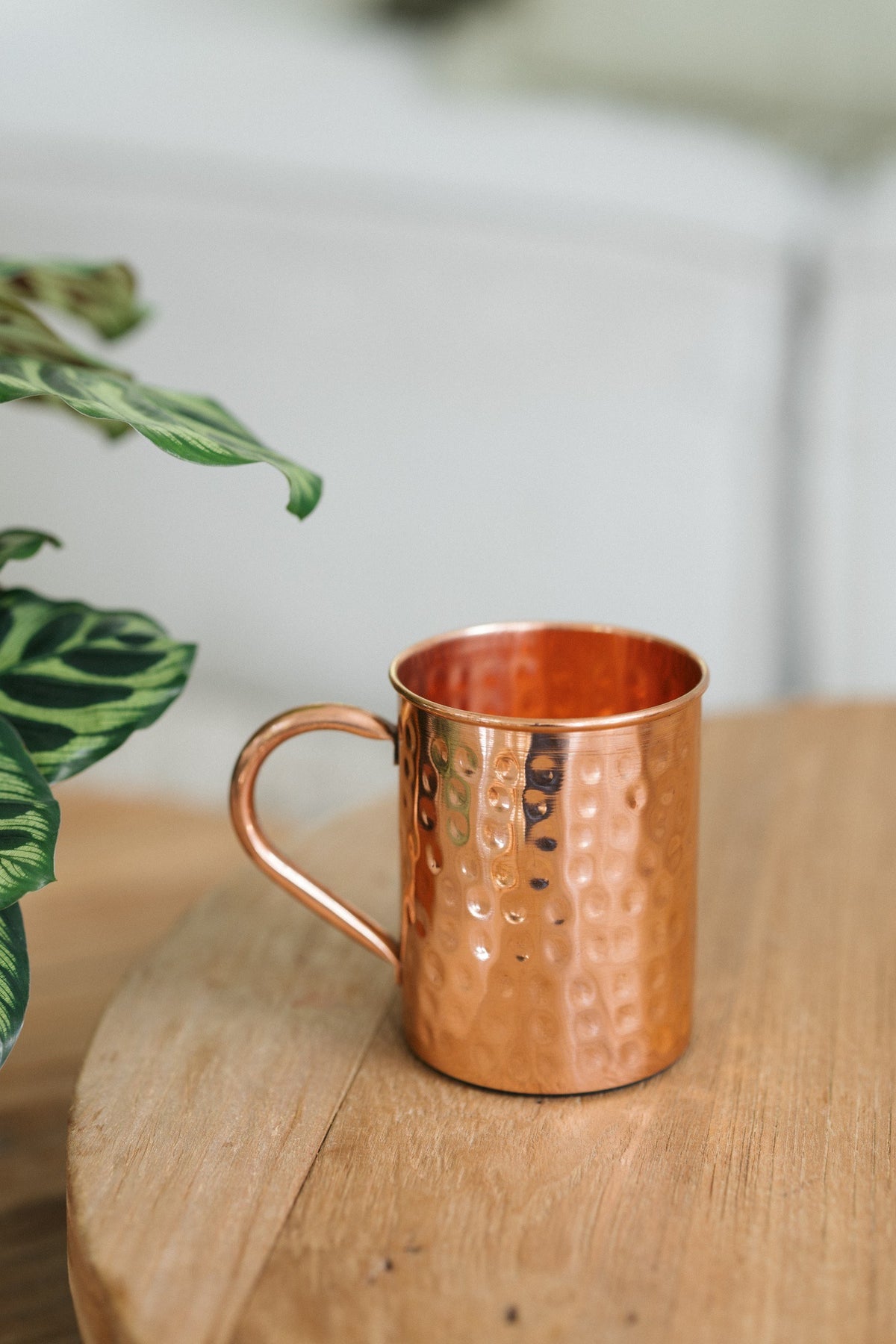 Kopero Mug en cuivre Martelé, sur une table ronde en bois devant un canapé