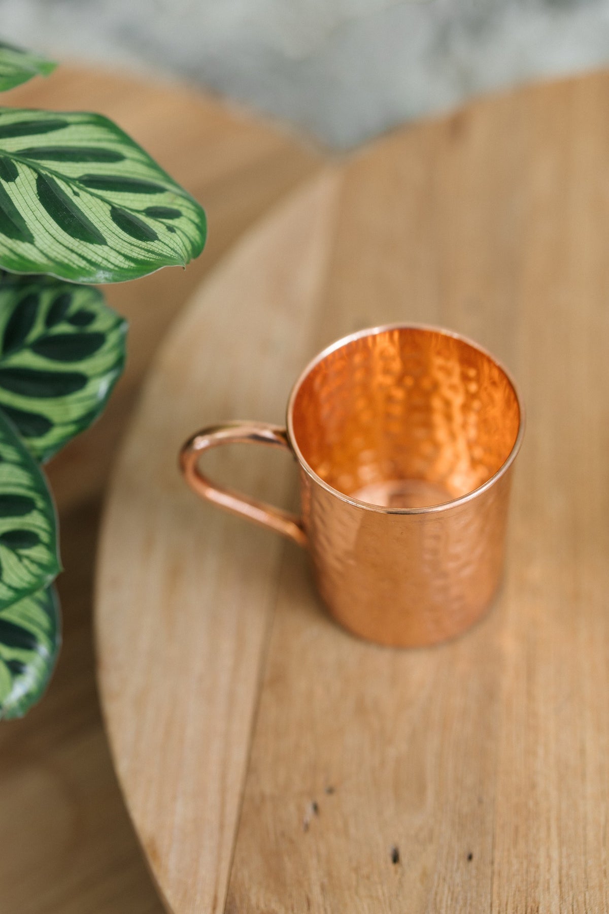 Kopero Mug en cuivre Martelé, couché sur le côté sur une table ronde en bois