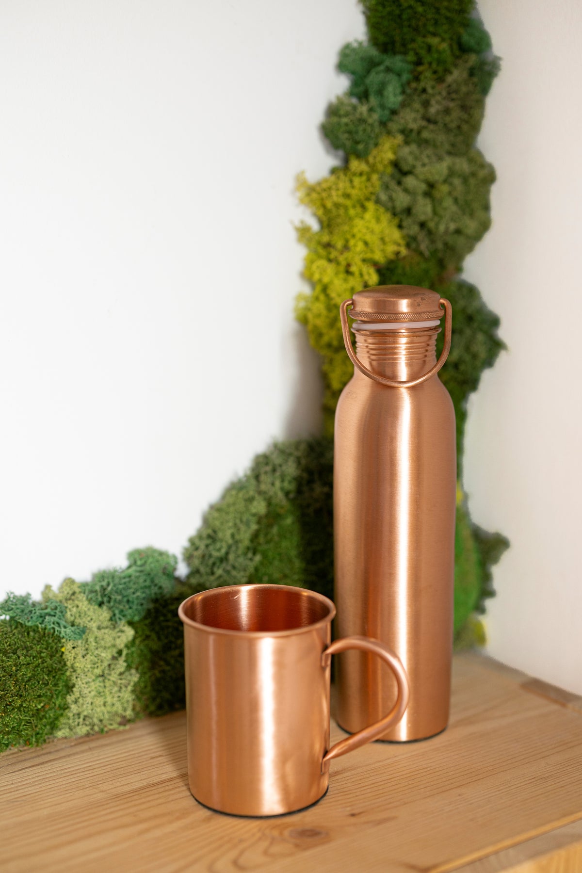 Mug en cuivre Kopero Premium Lisse à côté d'une gourde en cuivre de la collection Kopero