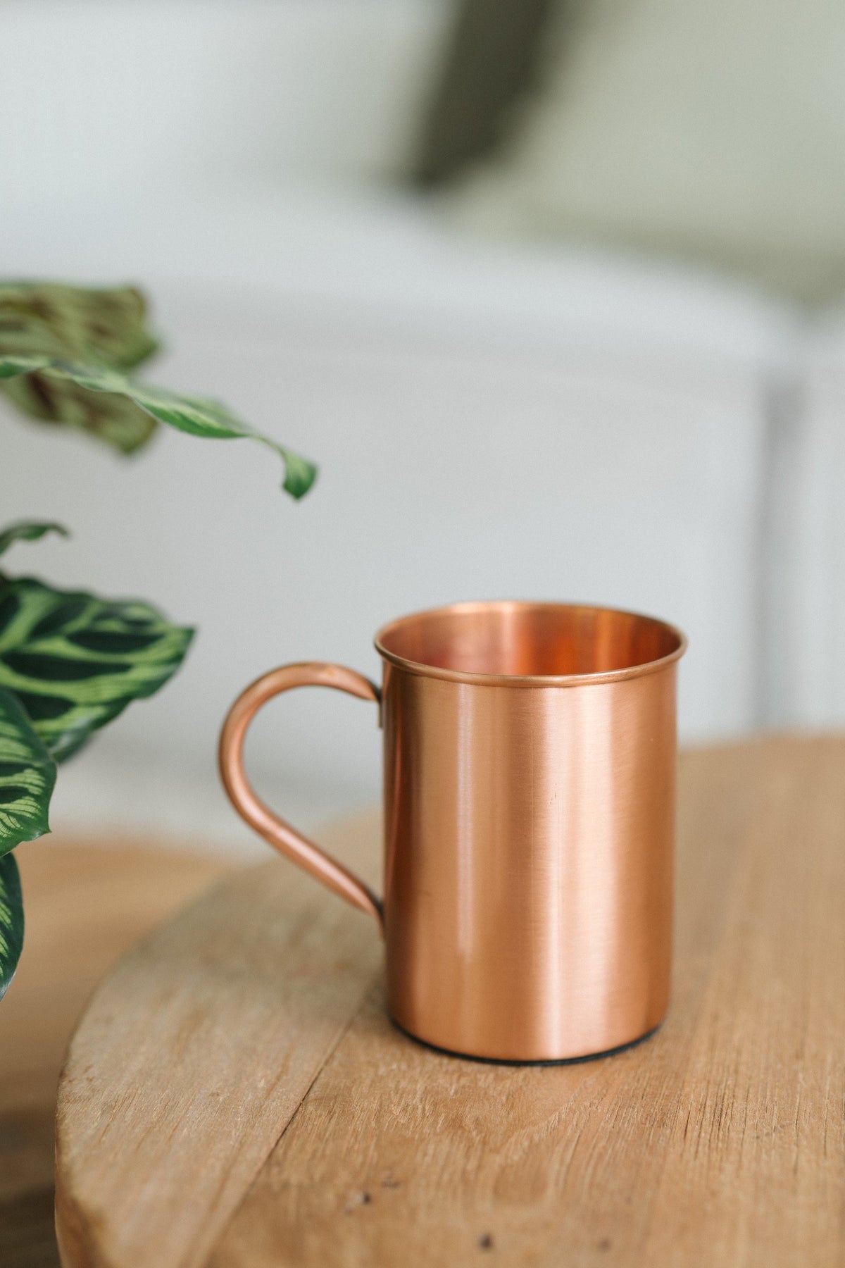 Kopero Mug en cuivre Lisse, sur une table ronde en bois devant un canapé