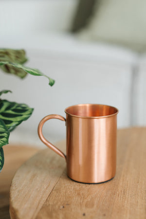 Kopero Mug en cuivre Lisse, sur une table ronde en bois devant un canapé