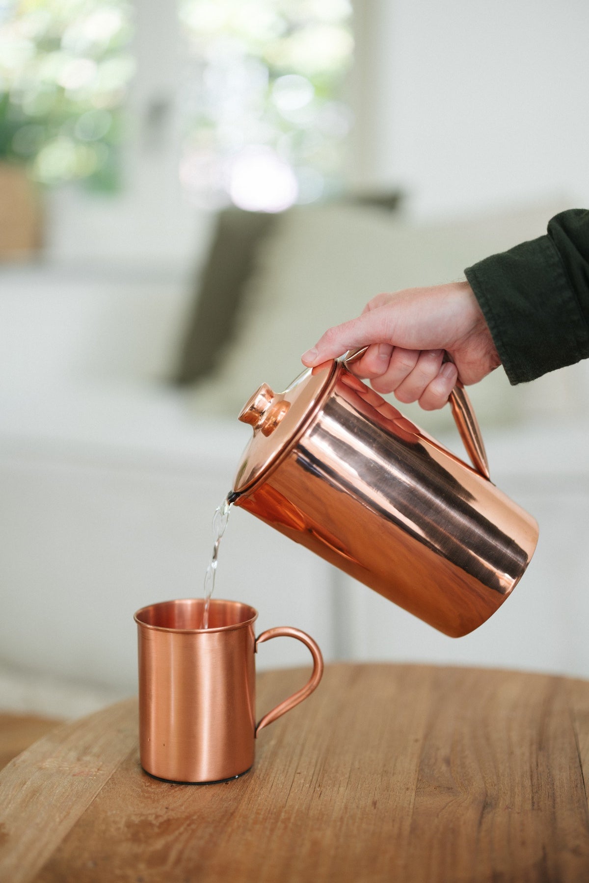 Kopero Mug en cuivre Lisse, pendant que de l'eau y est versée depuis une cruche en cuivre