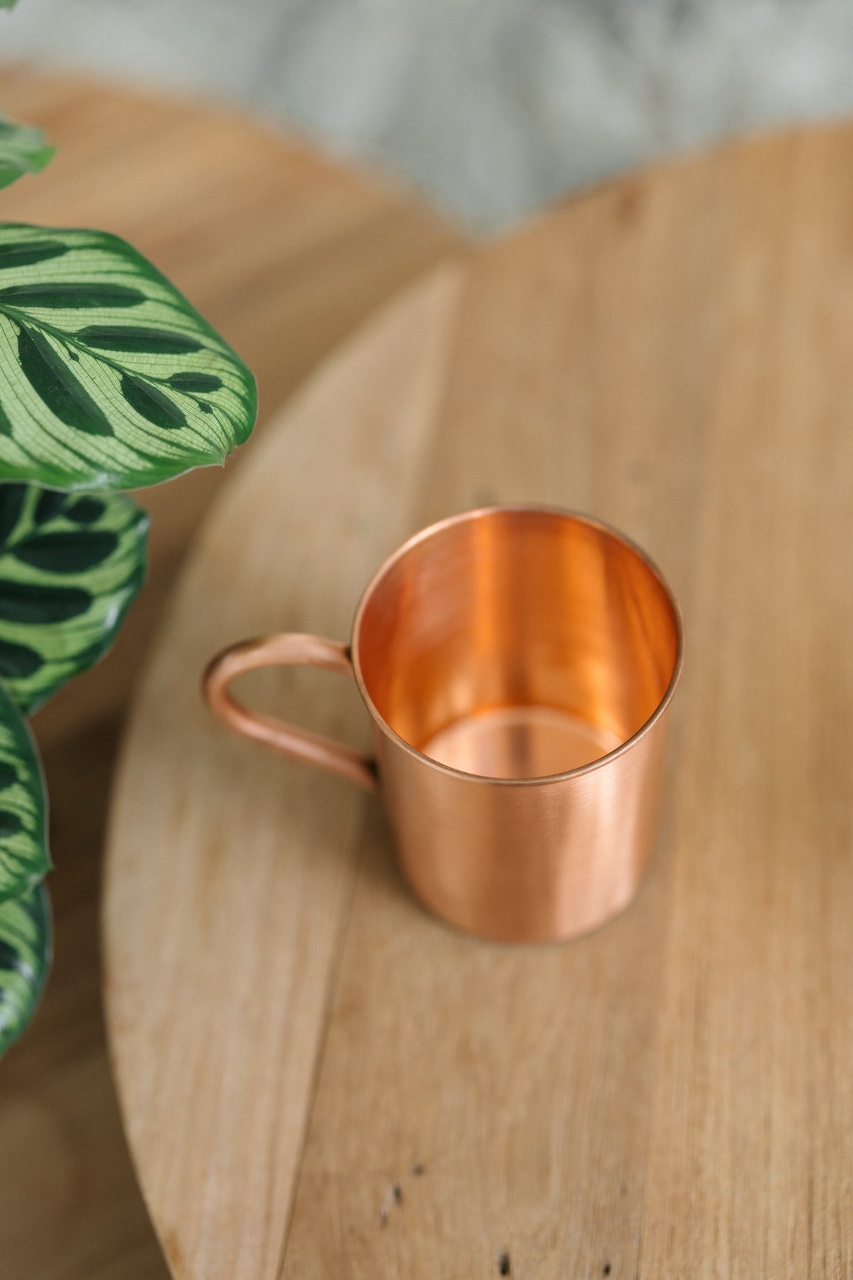 Kopero Mug en cuivre Lisse, couché sur le côté sur une table ronde en bois