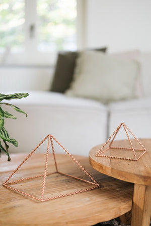 Kopero Pyramide énergisante en cuivre torsadé, la petite et la grande pyramide côte à côte sur deux tables en bois