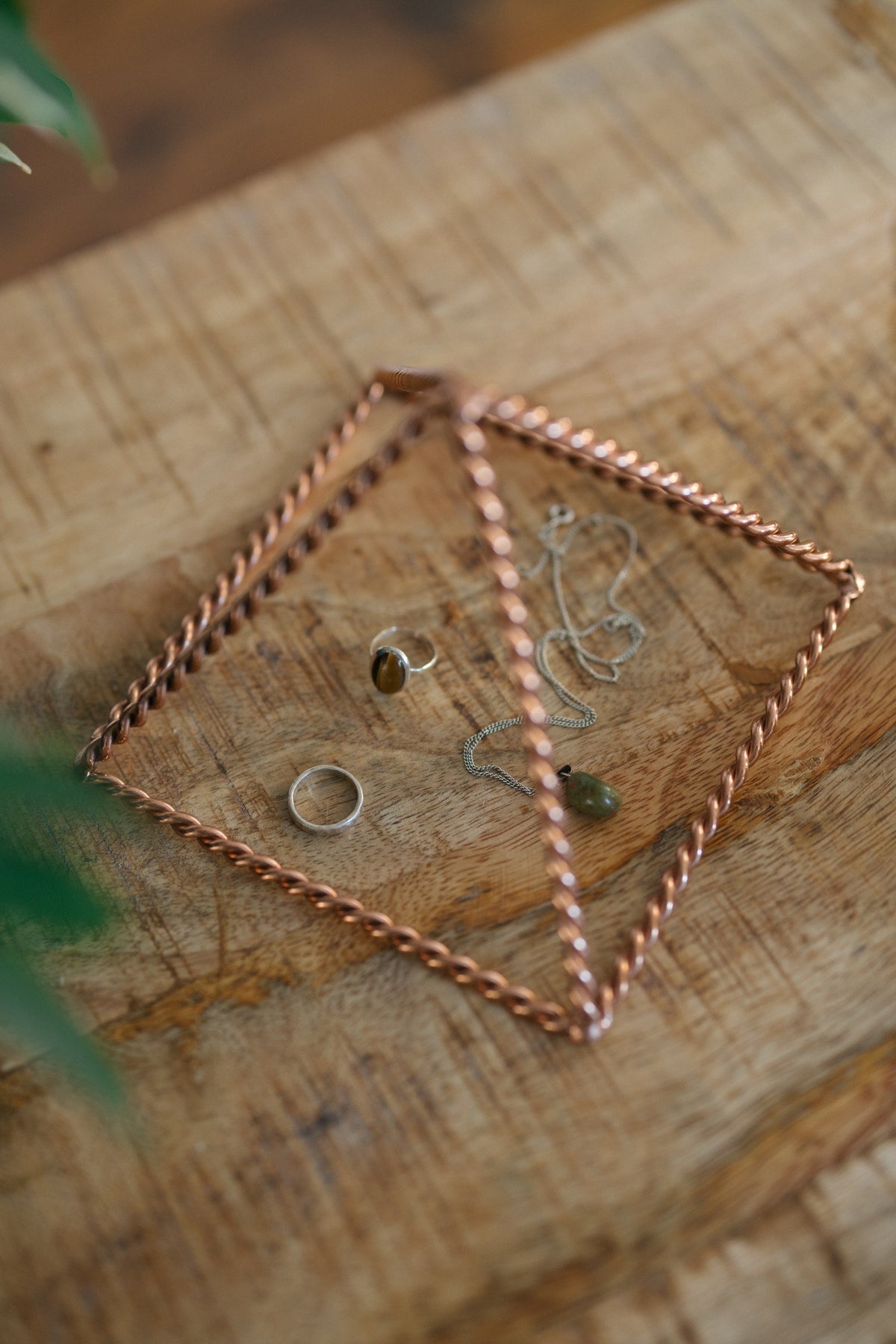 Kopero Pyramide énergisante en cuivre torsadé Petite (14,56 cm), avec des bijoux dessous sur une planche en bois