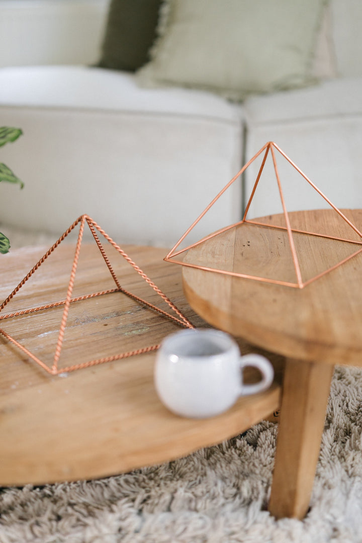 La grande pyramide lisse et la grande pyramide torsadée sur deux tables en bois, avec un mug