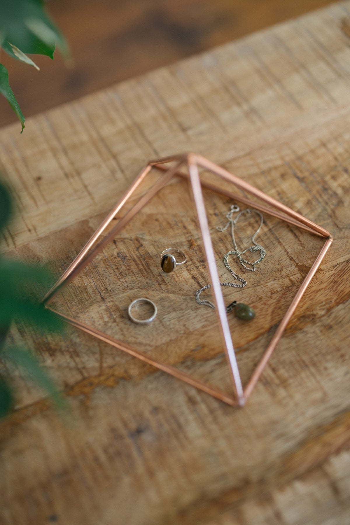 Kopero Pyramide énergisante en cuivre lisse Petite (14,56 cm), avec des bijoux dessous sur une planche en bois