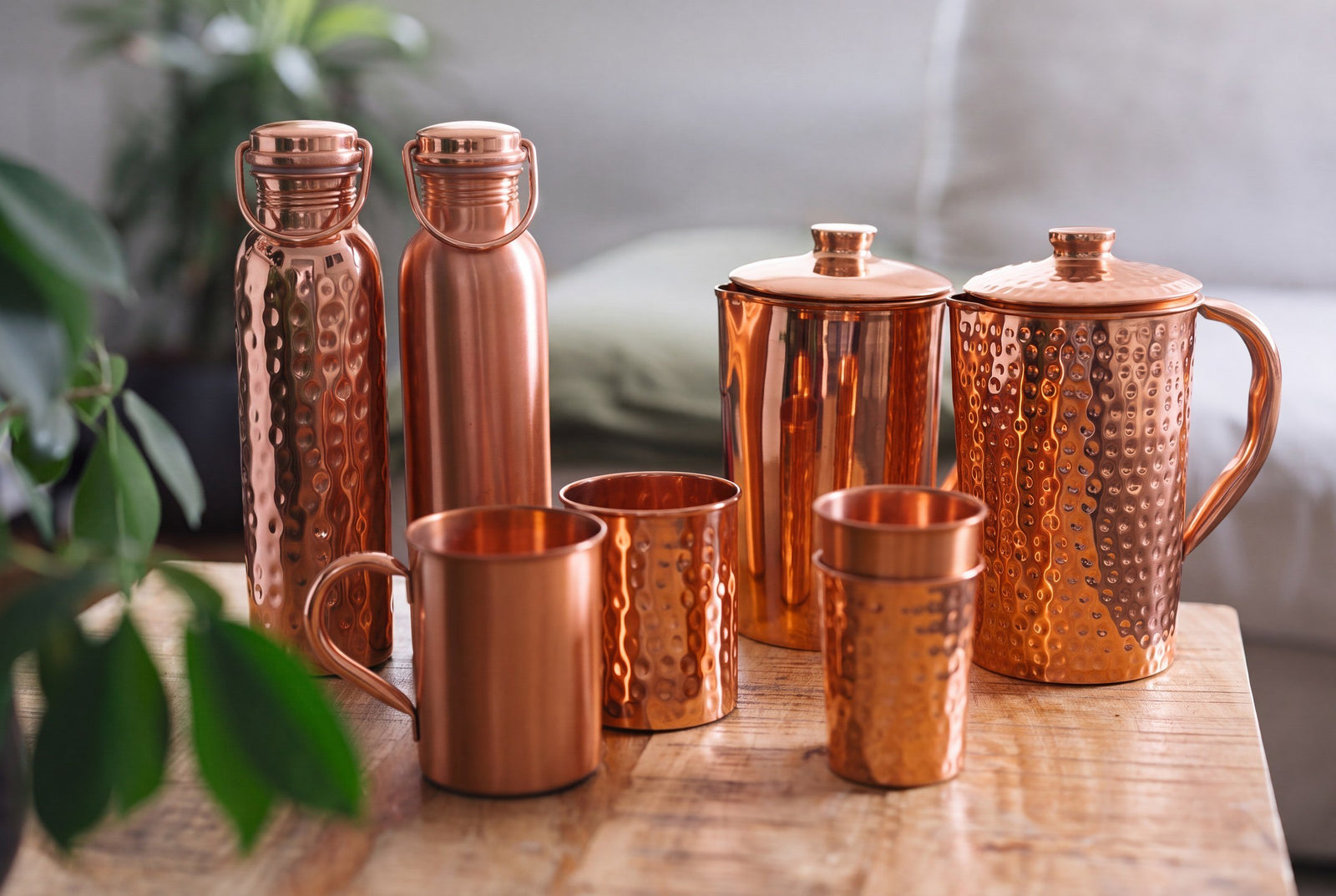 Gourdes, cruches, mugs et gobelets en cuivre, lisses et martelés, ensemble sur une table en bois