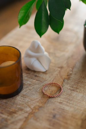 Kopero Anneau tenseur en cuivre, sur une table en bois à côté d'un bougeoir en verre et d'une figurine