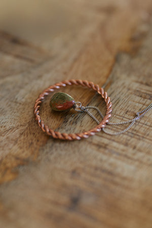 Kopero Anneau tenseur en cuivre, sur une table en bois avec un pendentif en unakite